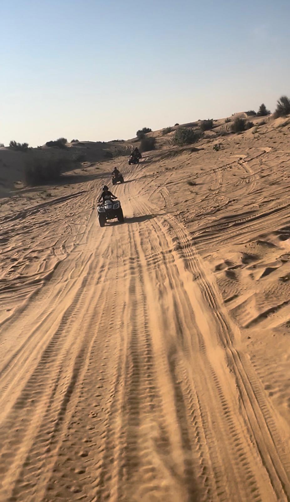 Line of ATVs riding through Dubai desert at sunset